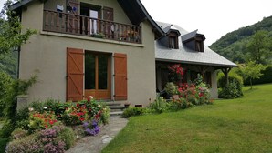 A two-story house with a balcony, wooden shutters, and a garden with various flowers. - Beautiful, independent, quiet apartment (Luz-Saint-Sauveur)