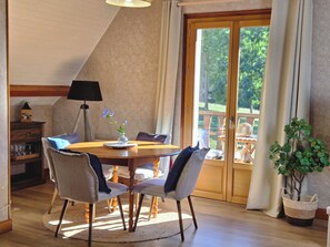 A dining area with a round table, chairs, a lamp, and a view through a glass door. - Your charming getaway in the heart of the Pyrenees (Luz-Saint-Sauveur)