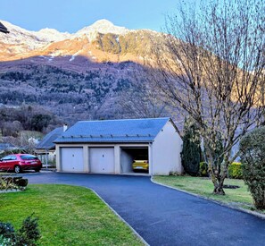 A building with a garage, a red car parked in front, and a mountainous backdrop. - Your charming getaway in the heart of the Pyrenees (Luz-Saint-Sauveur)