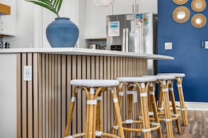 Una cocina con una encimera blanca, un jarrón azul y un refrigerador de acero inoxidable.