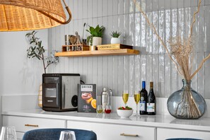 Een keuken met een koffieapparaat, een boek getiteld 'COCKTAILS' en flessen wijn.