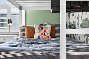 Ein Schlafzimmer mit einem Bett, Kissen, einer Lampe und einer Wand mit Surfbrett und Autosticker.