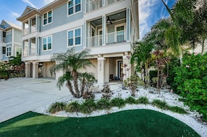 A multi-story residential building with balconies, a driveway, and landscaped garden areas.