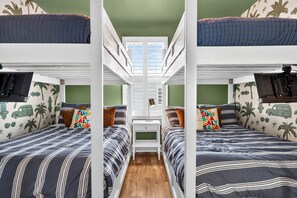 Een slaapkamer met een stapelbed, een centraal bureau, groene wanden en een raam.