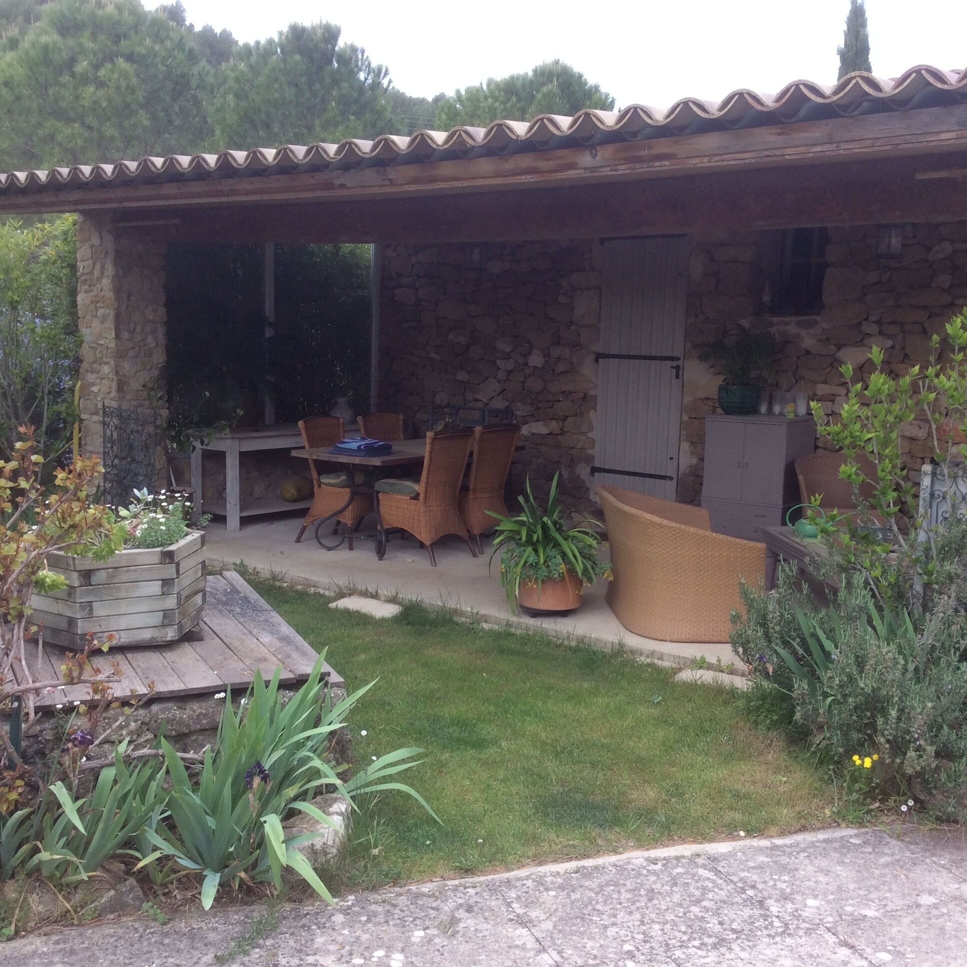 A stone house with a covered patio, outdoor seating, and potted plants.