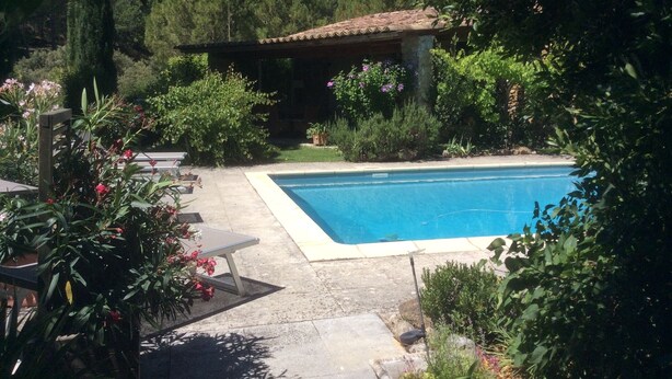 A swimming pool surrounded by lush greenery, a stone building, and a patio area with a table and chairs. - SHEEP IN THE REGIONAL PARK LUBERON (Lauris)