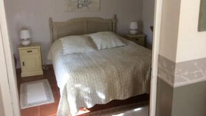 A bedroom with a bed, two bedside tables, a nightstand, a decorative wall piece, and a small rug. - SHEEP IN THE REGIONAL PARK LUBERON (Lauris)