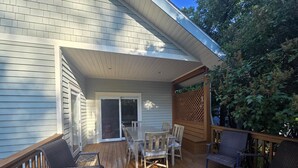 Una terraza techada con una mesa y sillas, una puerta corrediza de vidrio y una valla de madera.