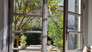 An open door leading to a garden with potted plants and a bench. - Charming villa with swimming pool close to the center of St Rémy de Provence 4-6 (Saint-Rémy-de-Provence)