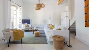 A modern living room with white sofas, a coffee table, and a TV. There are wicker ottomans and a hanging light fixture. - Charming villa with swimming pool close to the center of St Rémy de Provence 4-6 (Saint-Rémy-de-Provence)