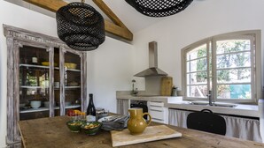 A kitchen with a wooden table, a yellow pitcher, and a window with a view of trees. - Charming villa with swimming pool close to the center of St Rémy de Provence 4-6 (Saint-Rémy-de-Provence)