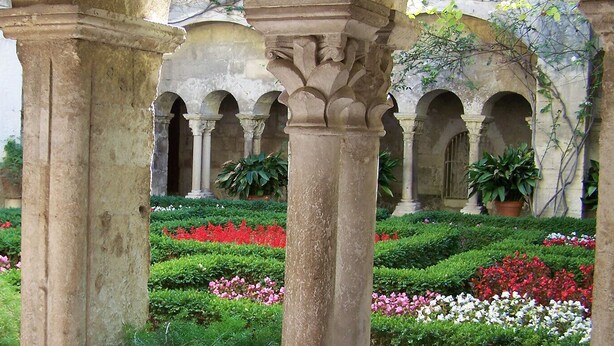 A courtyard with stone columns and arches, surrounded by well-maintained hedges and flowering plants. - Charming villa with swimming pool close to the center of St Rémy de Provence 4-6 (Saint-Rémy-de-Provence)