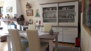 Een eethoek met een houten tafel, stoelen en een kast met glazen deuren waar servies wordt uitgestald.