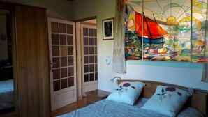 Slaapkamer met een bed, een houten kledingkast, een glazen deur, een kleurrijk glas-in-loodraam en een decoratie met de Davidster.