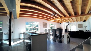 Una cocina moderna con una isla central, un comedor con sillas y una escalera que sube a otro nivel.