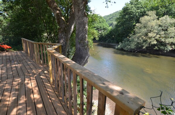 Eine Holzterrasse mit Blick auf einen Fluss, umgeben von Bäumen.
