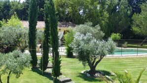 A well-maintained garden with various trees, a swimming pool, and a house with a tiled roof. - Gîte de provence jacuzzi (Velleron)