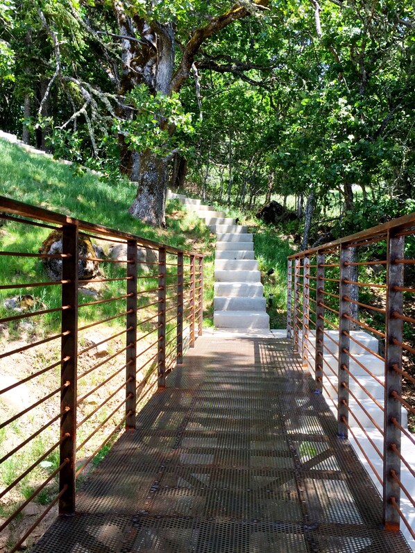 A metal bridge with a metal railing and a concrete staircase leading up to it.