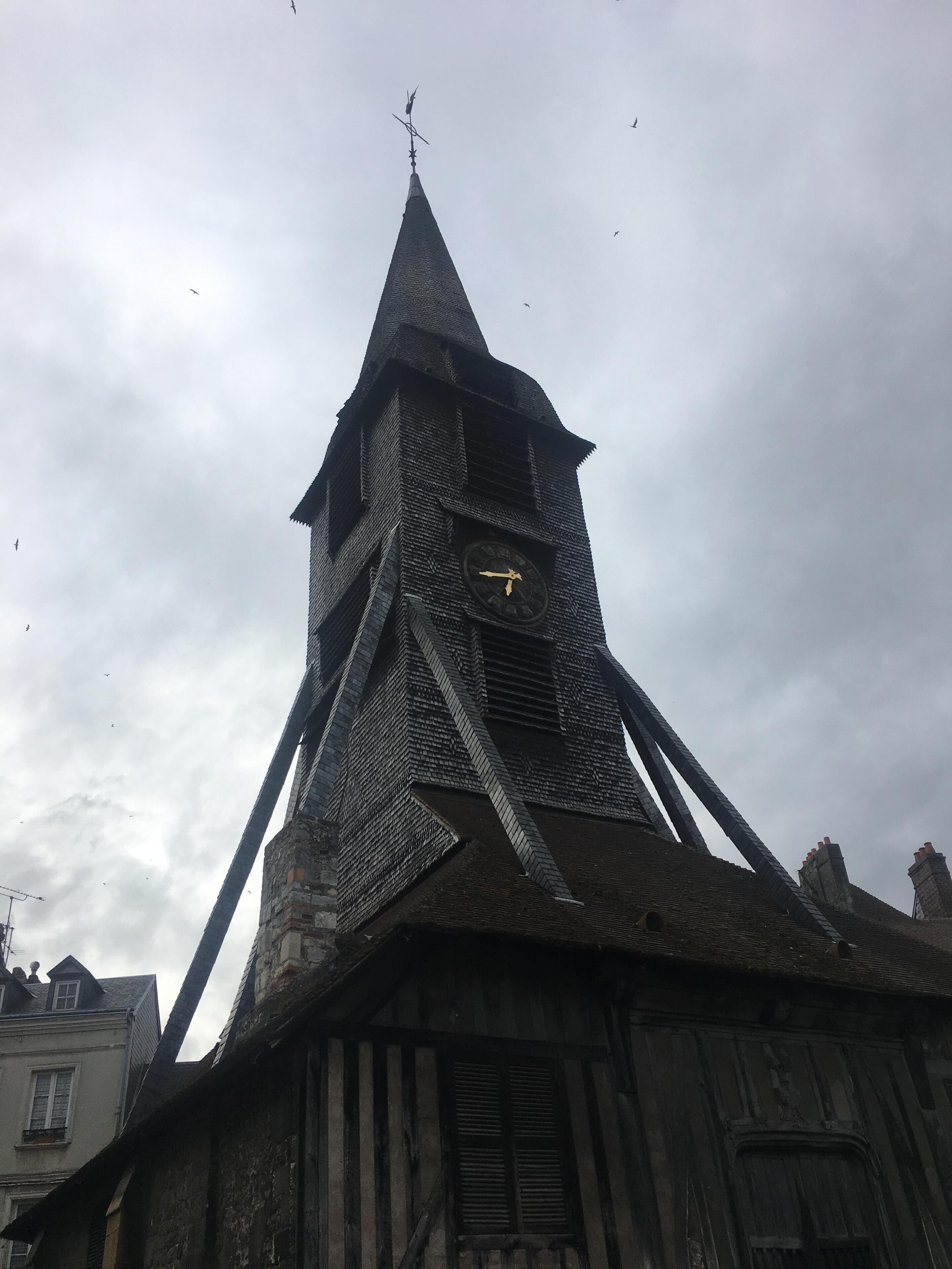 A historic building with a prominent tower featuring a clock and a weather vane.
