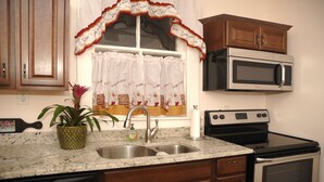 Una cocina con un lavaplatos doble, estufa, microondas y armarios de madera.
