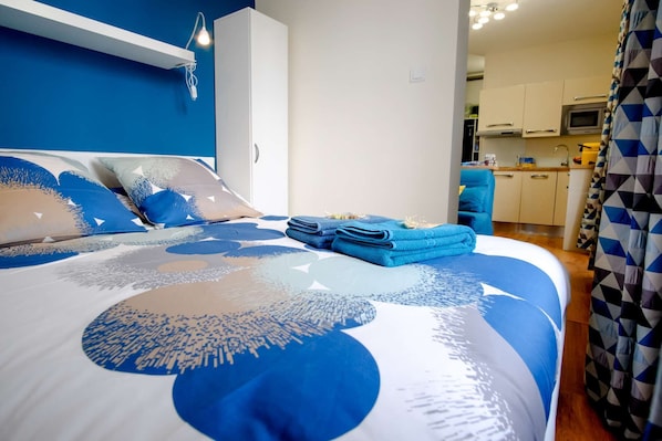 Une chambre avec un lit, un bureau et un coin cuisine.