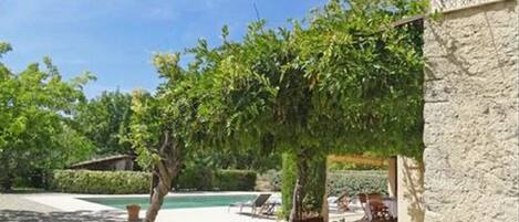 Relax by the pool surrounded by a pergola and lounge chairs.