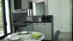 A modern kitchen with a dining area, featuring a microwave, stove, sink, and a coffee maker. - Comfortable cottage 3 *** in the Vaunage (Boissières)