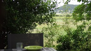 A table set outdoors with a view of a green field and distant buildings. - Comfortable cottage 3 *** in the Vaunage (Boissières)
