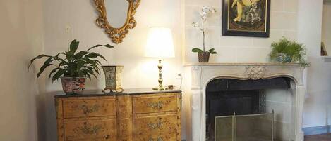 A room with a fireplace, a decorative mirror, a lamp, and a potted plant.