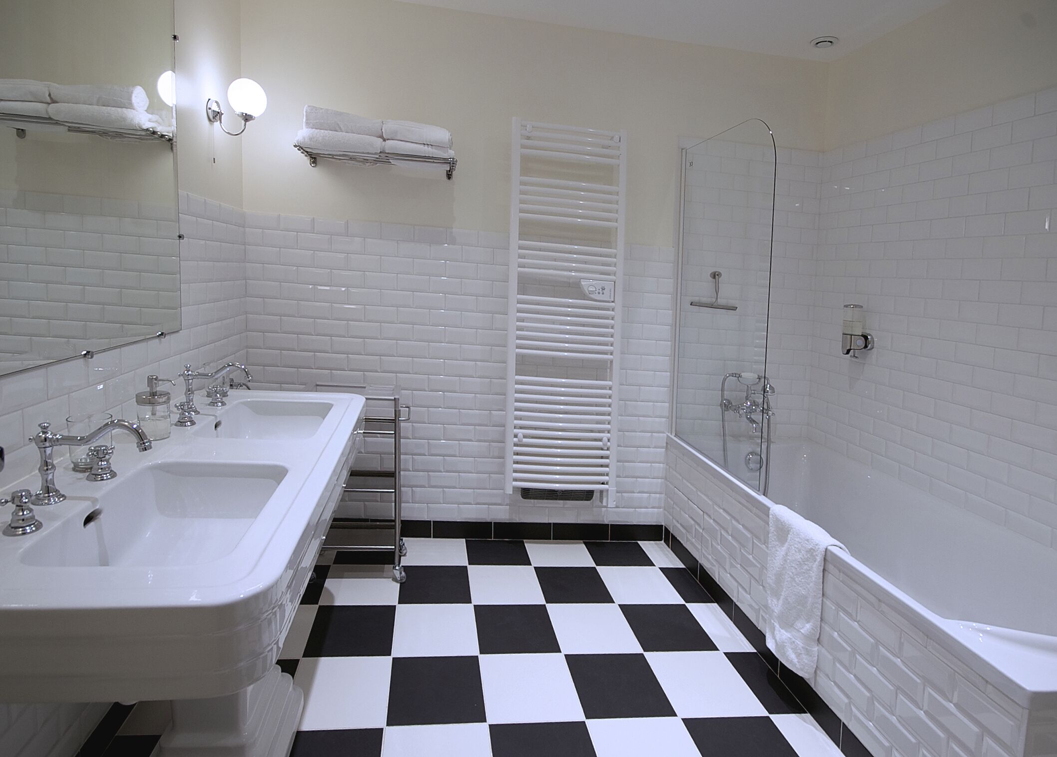 A bathroom with two sinks, a shower, and a checkered floor.