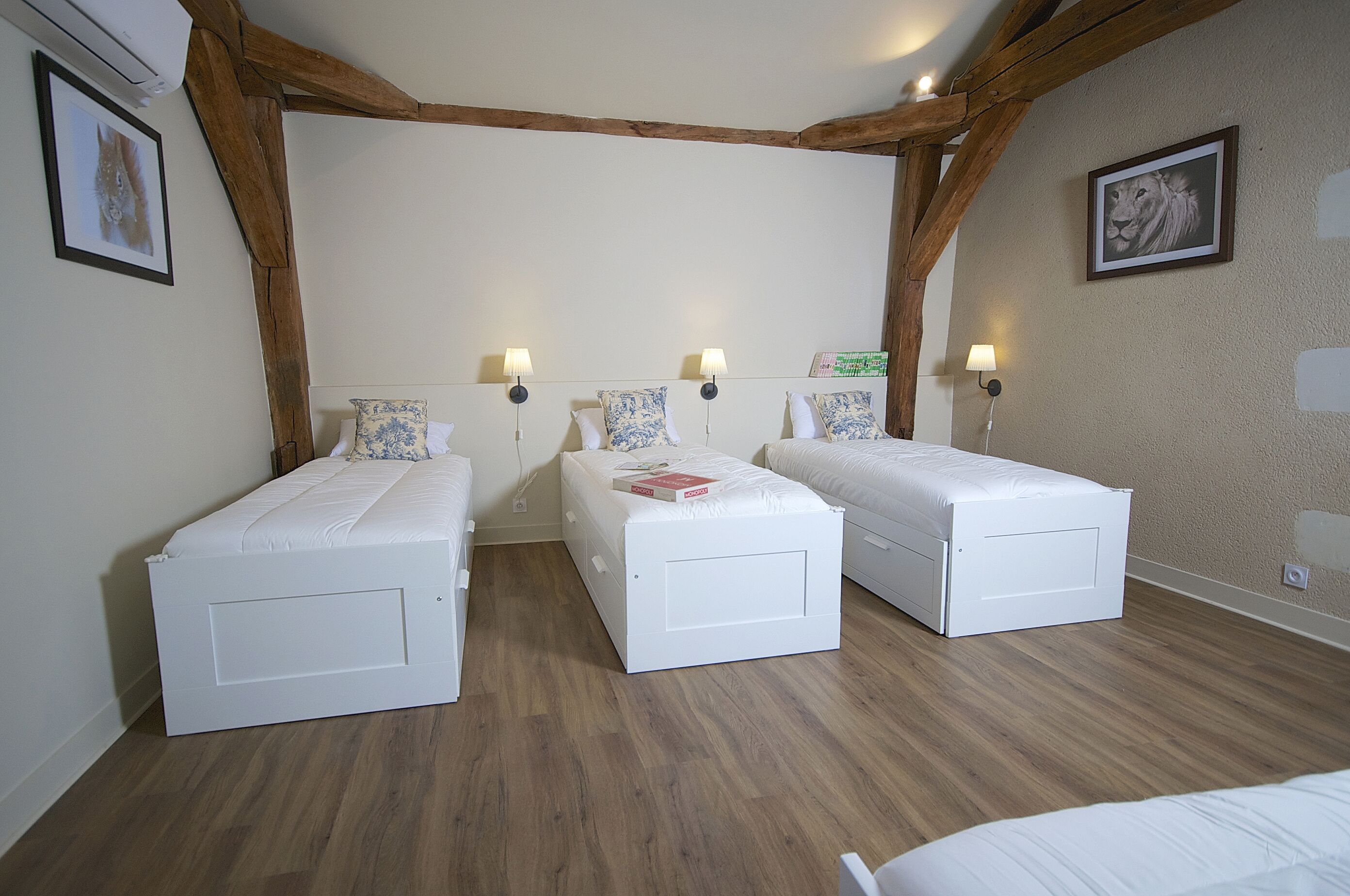 A room with two single beds, wooden beams, white walls, and two bedside lamps.