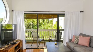 A living room with a TV, sofa, table, and chairs. - Beautiful Princeville Condo (Princeville)