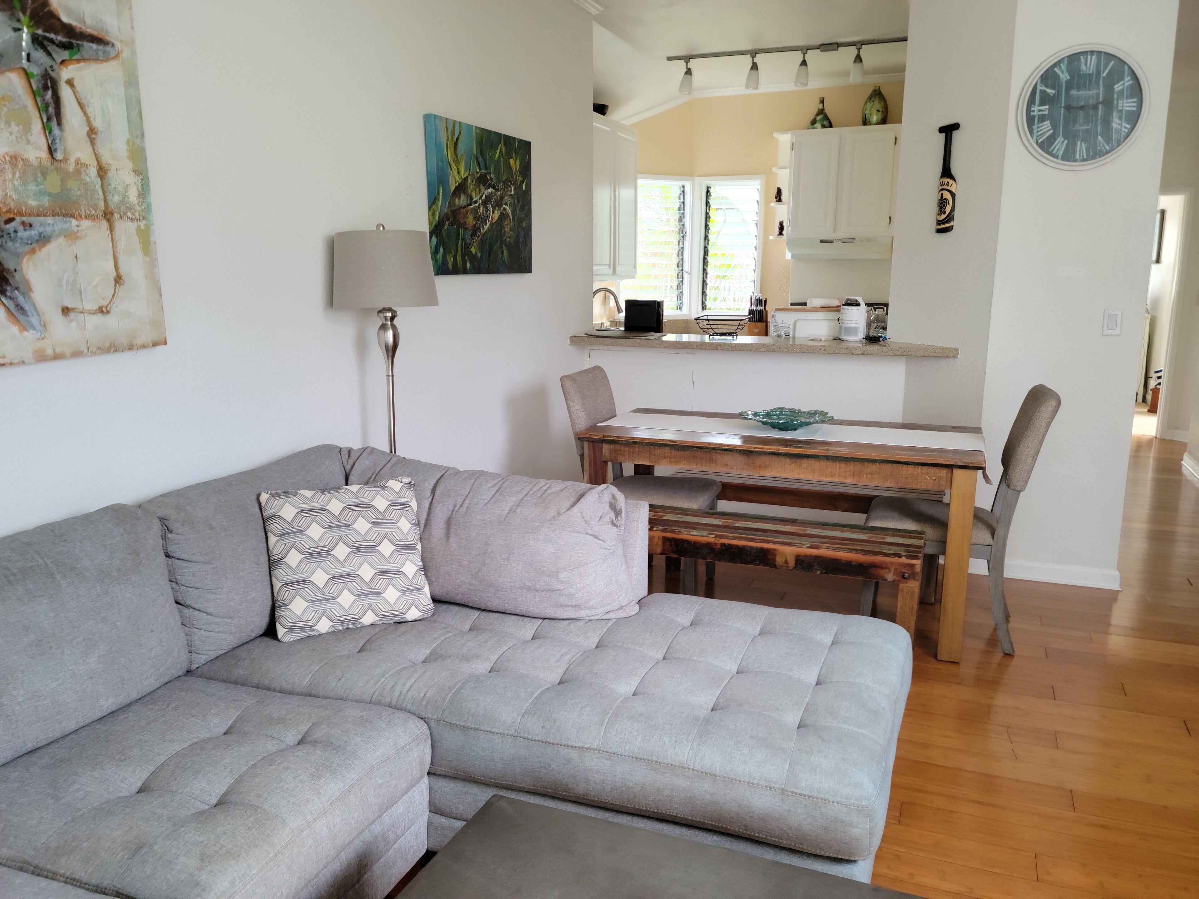 Un salon moderne avec un canapé gris, une table à manger et une cuisine en arrière-plan.