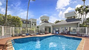 A swimming pool with lounge chairs and a covered area with tables and chairs. - Beautiful Princeville Condo (Princeville)