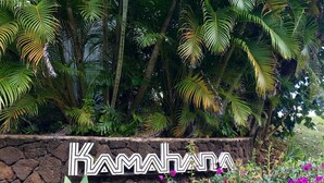 A stone wall with the name "KAMATHA" and lush tropical plants and flowers. - Beautiful Princeville Condo (Princeville)