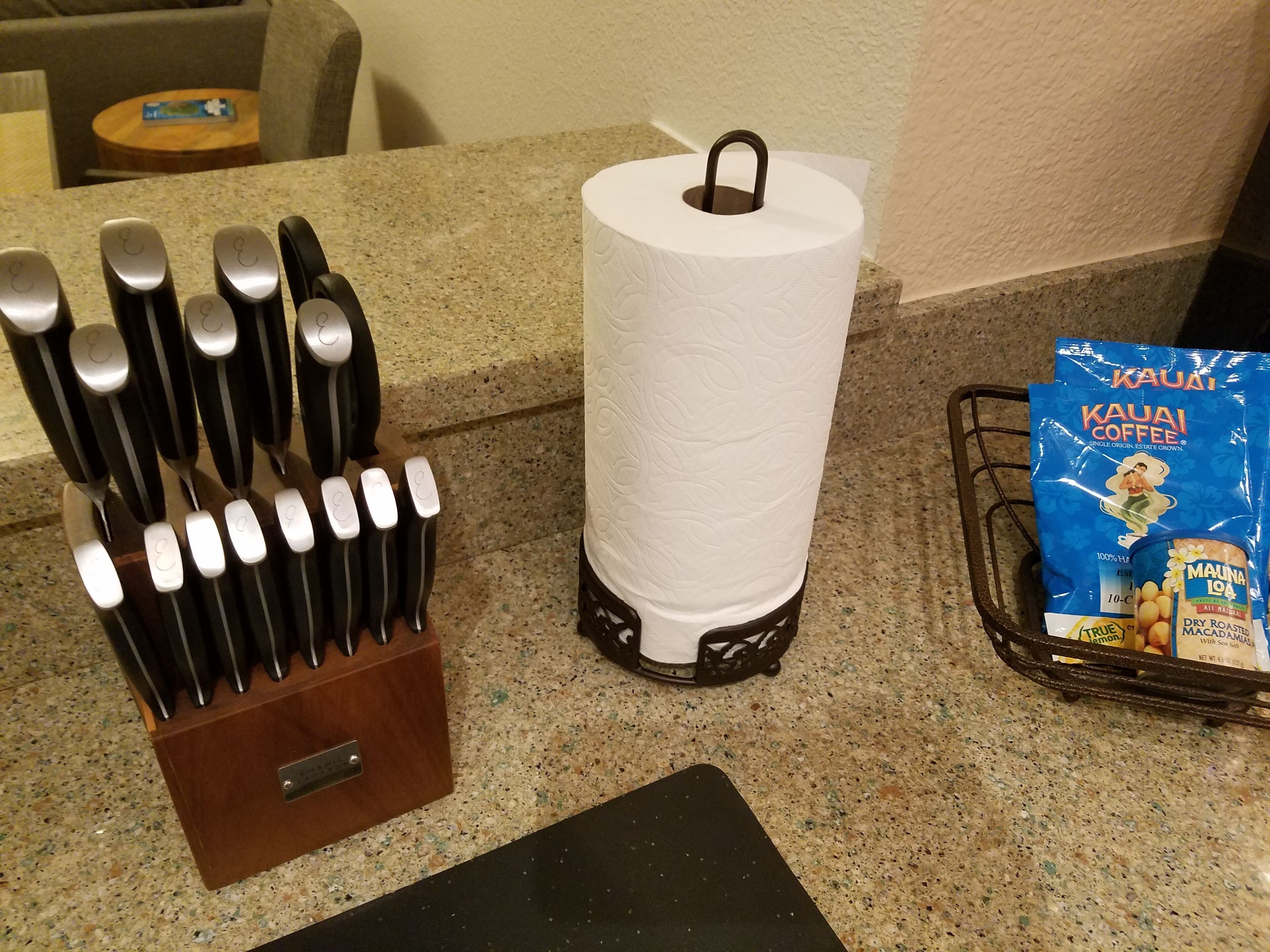 A kitchen counter with a paper towel holder, a set of knives, and a coffee bag.