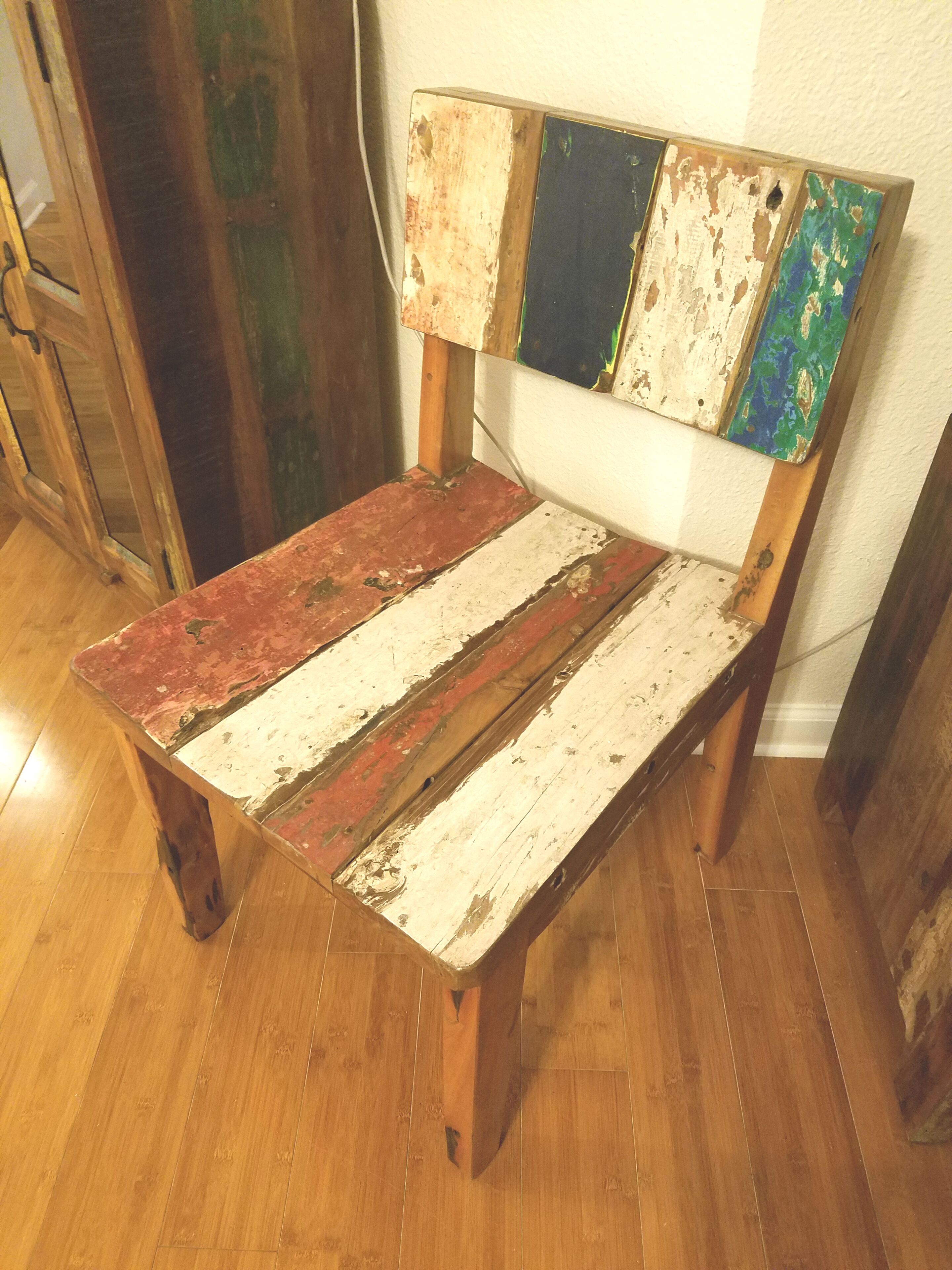 Un banc en bois rustique, doté d’une finition vieillie et d’une tête de lit colorée, peinte.