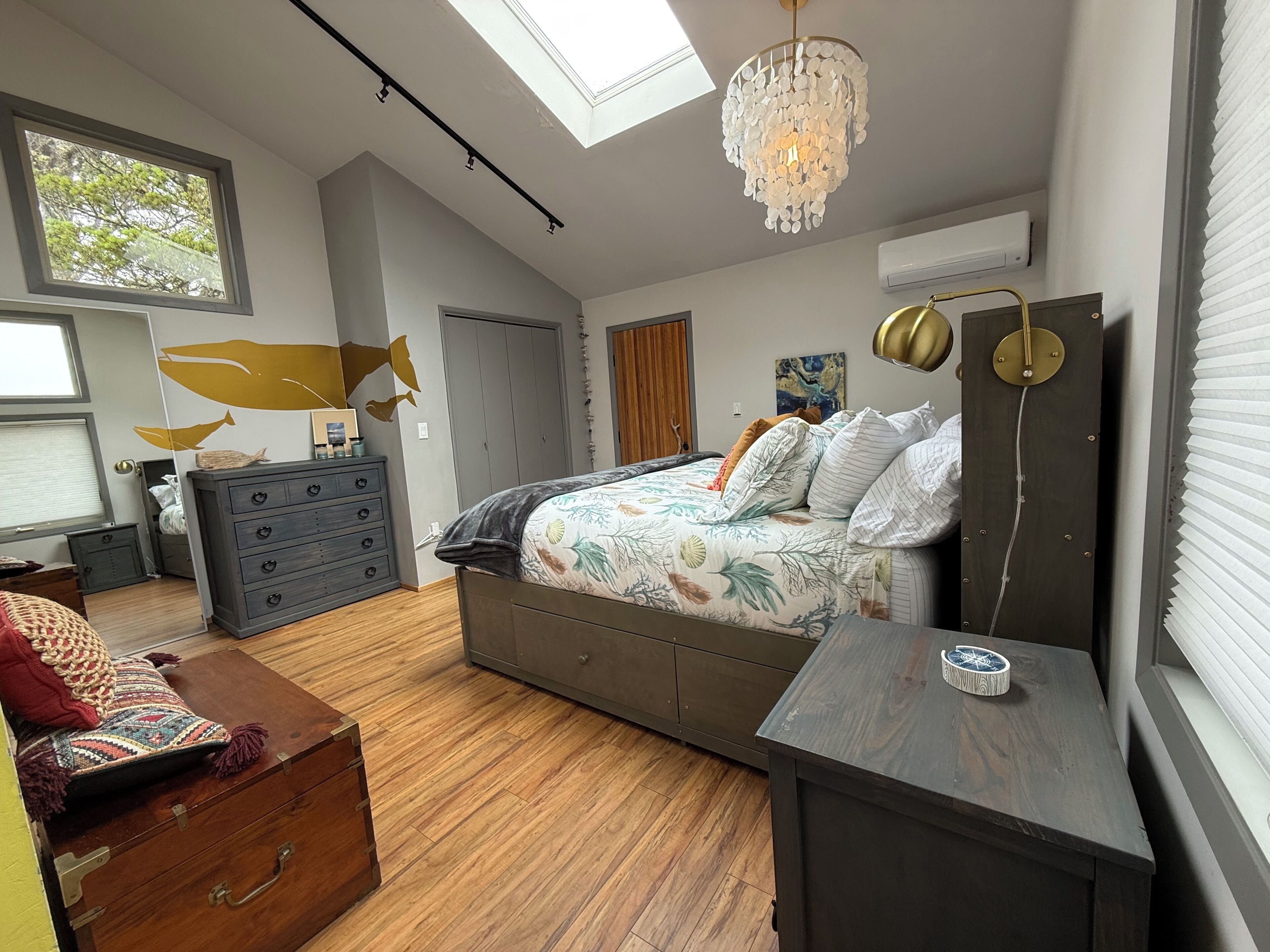 A bedroom with a bed, dresser, chest of drawers, and a desk.