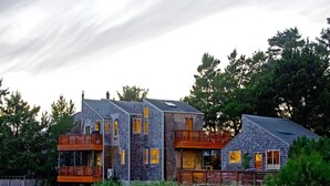 A modern multi-story house with a stone facade, multiple balconies, and a well-maintained garden.