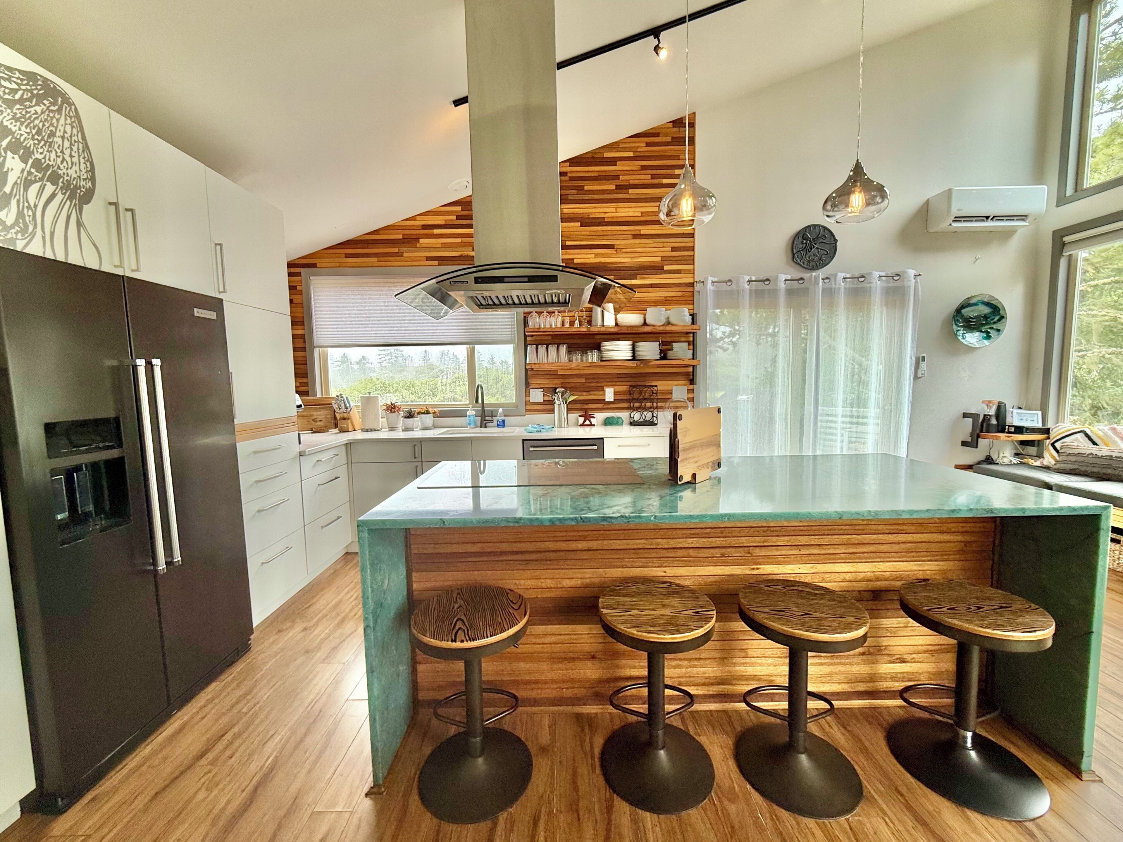 A modern kitchen with a central island, bar stools, and a wooden accent wall.