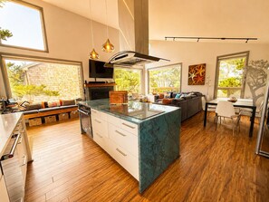 Cocina moderna con una isla central, suelo de madera y ventanas amplias.