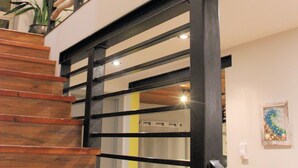 A wooden staircase with black railings and a modern light fixture.