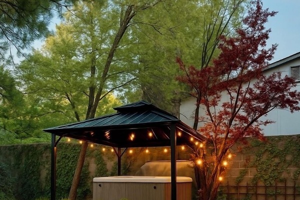 Outdoor spa with gazebo and string lights.