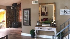 Un amplio salón con chimenea de piedra, un espejo grande y un tapete decorativo.