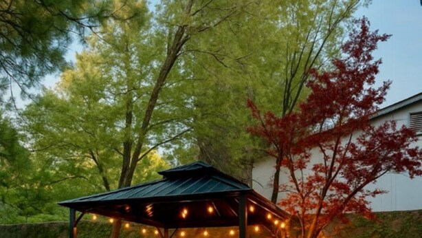 Un patio con jacuzzi, mobiliario exterior y una pérgola adornada con luces colgantes.
