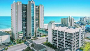 A high-rise hotel with multiple floors, a parking garage, and a view of the beach. - Clean 4th Floor Unit, Walk-In Shower, Outdoor Hot Tub | Windy Hill Dunes - 405 (North Myrtle Beach)