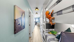 Ein Flur mit einem Gemälde einer Küstenlandschaft, Etagenbetten mit einem weichen Plüsch-Tintenfisch und einem Plüsch-Schildkröten-Spielzeug auf einem Bett.
