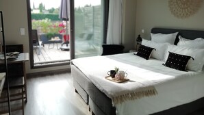 Un dormitorio moderno con una cama grande, una mesa de comedor y un ventanal corredero que da a un patio exterior.