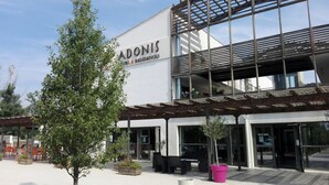 Un edificio moderno con un letrero que dice 'ADONIS HOTEL & RESIDENCES'.