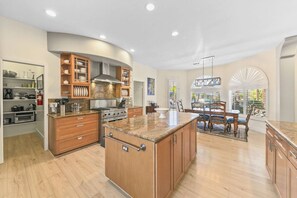 A spacious kitchen with a central island, wooden cabinetry, and a dining area with a view.